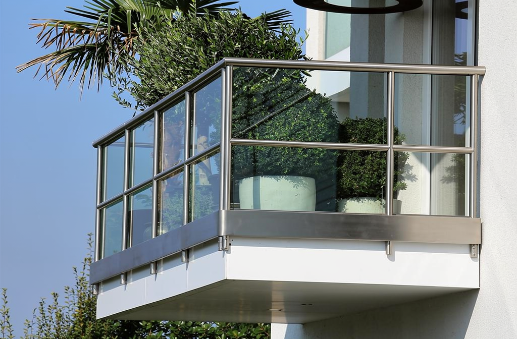 Garde-corps en verre feuilleté trempé installé sur un balcon moderne avec végétation.