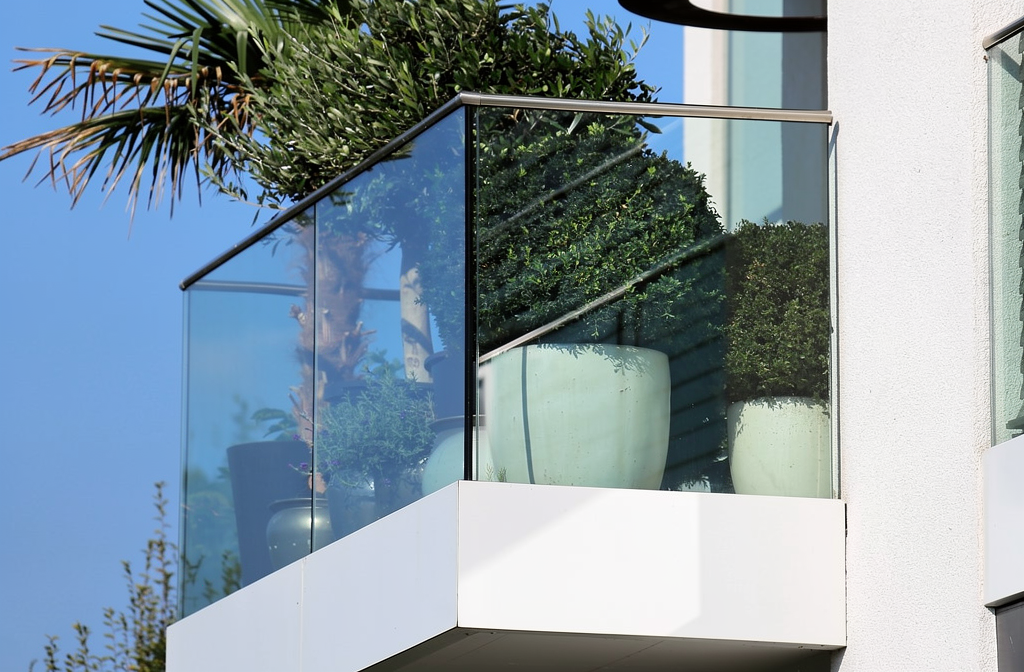 Garde-corps vitré moderne installé sur un balcon d'appartement avec plantes