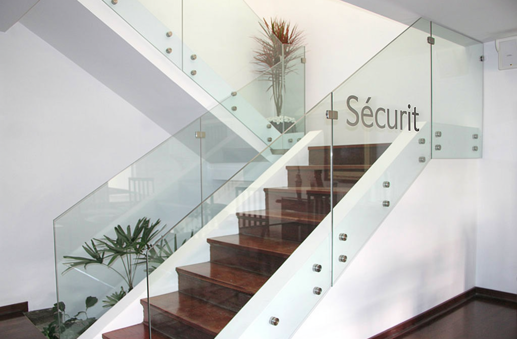 Garde-corps en verre trempé Sécurit transparent fixé sur un escalier en bois dans un intérieur moderne et lumineux.