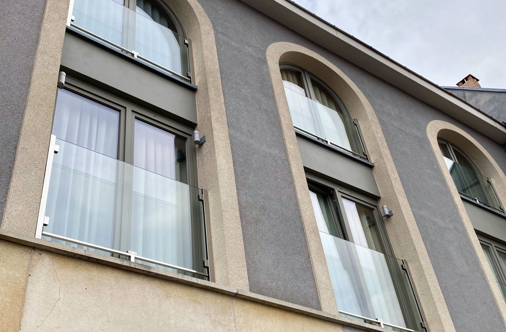 Garde-corps de fenêtre en verre installé sur une façade d'immeuble moderne respectant la hauteur réglementaire minimale.