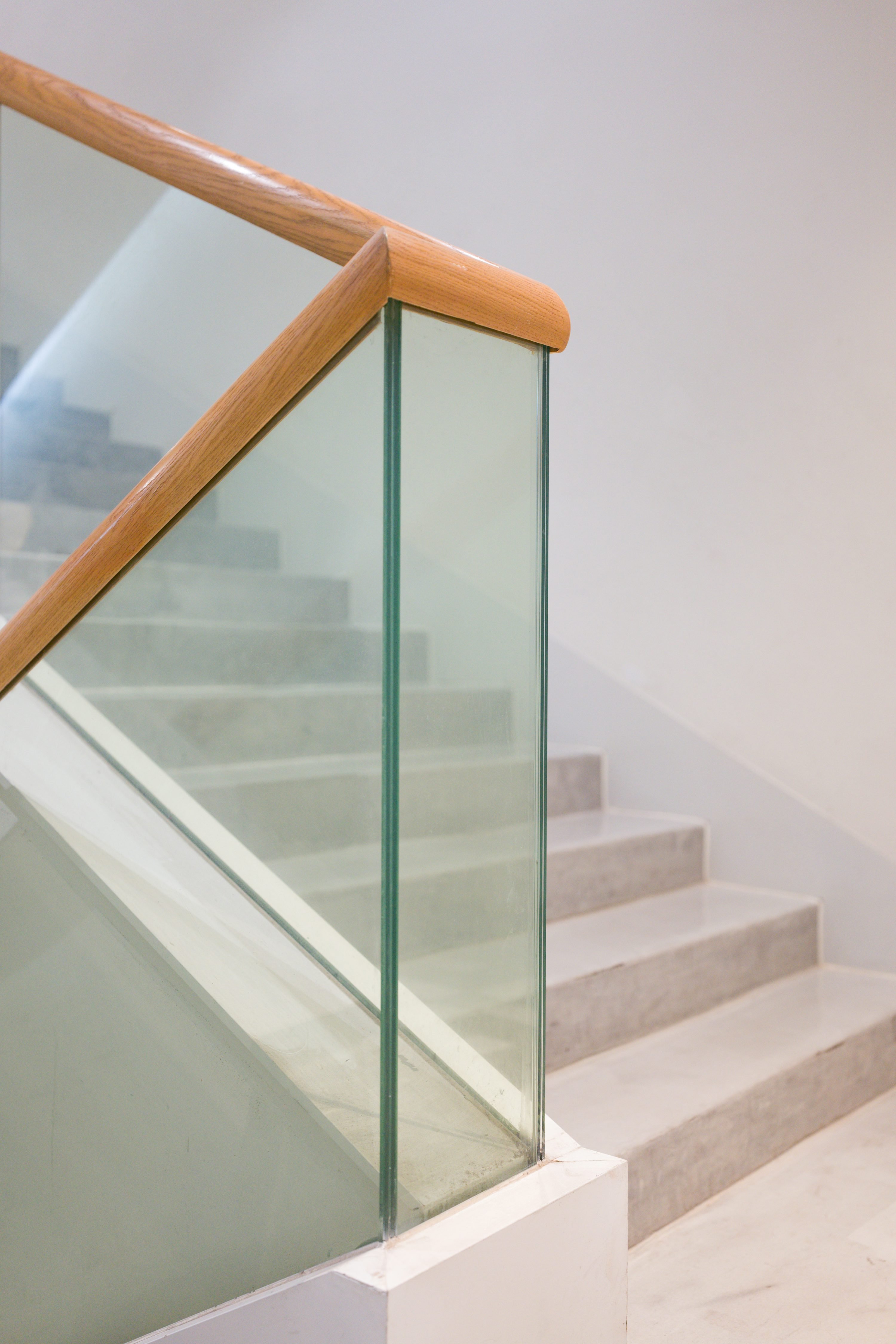 Garde-corps d’escalier en verre stratifé avec pin ou bois sur le dessus et main courante en bois.