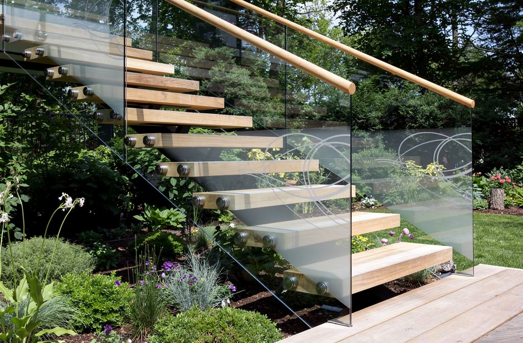 Garde-corps en verre extérieur unique longeant un escalier en bois sur une terrasse ensoleillée.