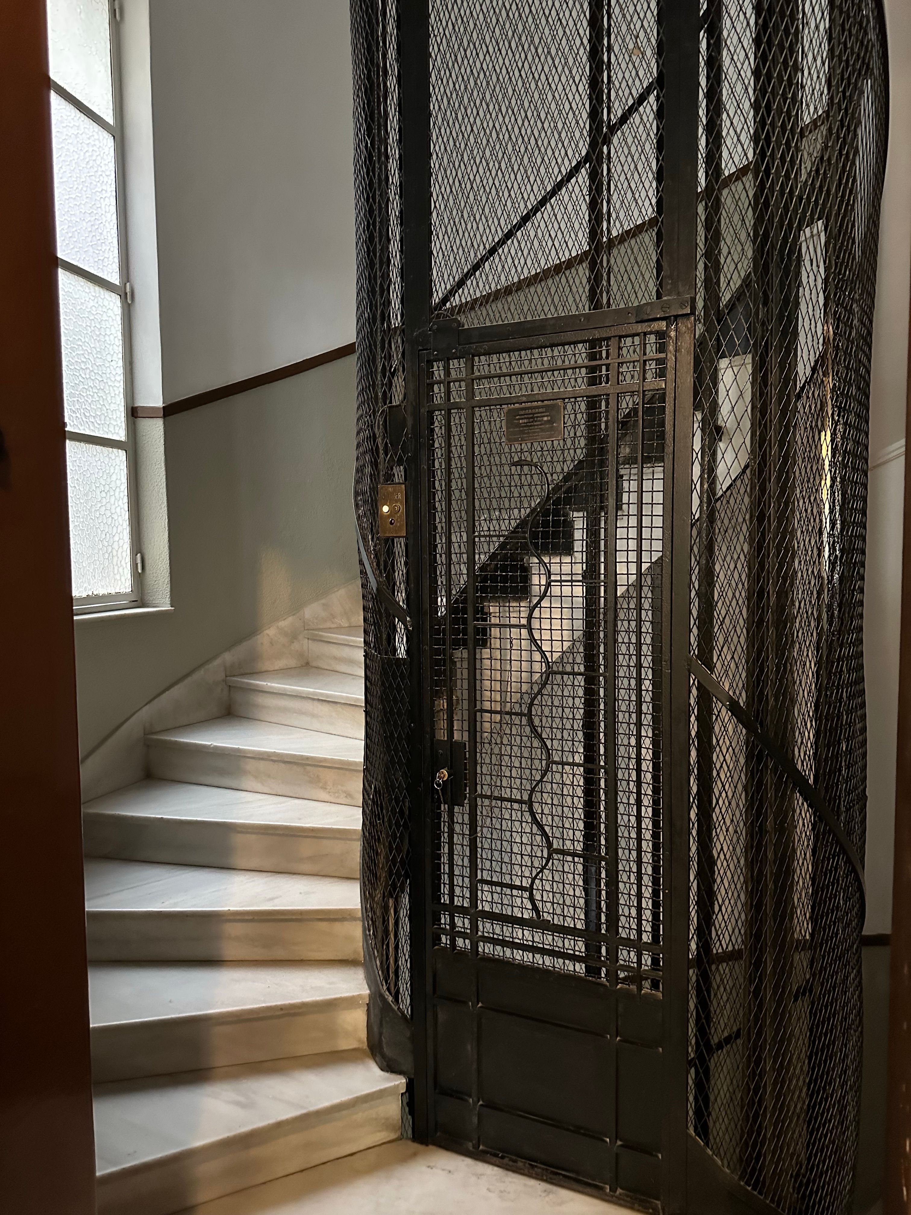 Portail et cage d’escalier en métal sécurisée entourant l’escalier en marbre avec une grille et un petit escalier sur la gauche